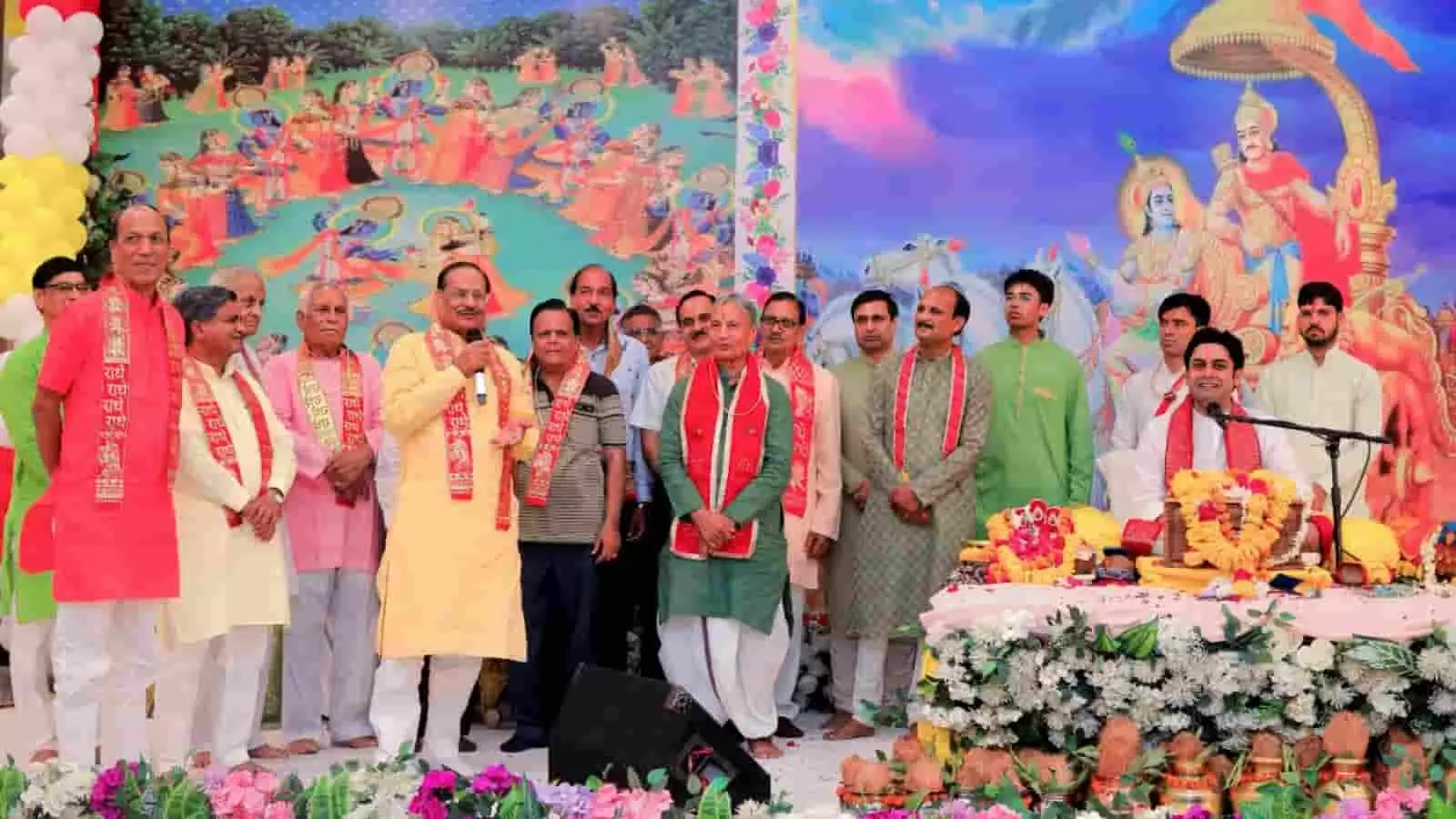 तस्वीर में एक भव्य धार्मिक मंच दिखाई दे रहा है, जिसकी पृष्ठभूमि में भगवान श्रीकृष्ण की रासलीला और महाभारत के प्रसंग का बड़ा चित्र लगा है तस्वीर में एक भव्य धार्मिक मंच दिखाई दे रहा है, जिसकी पृष्ठभूमि में भगवान श्रीकृष्ण की रासलीला और महाभारत के प्रसंग का बड़ा चित्र लगा है