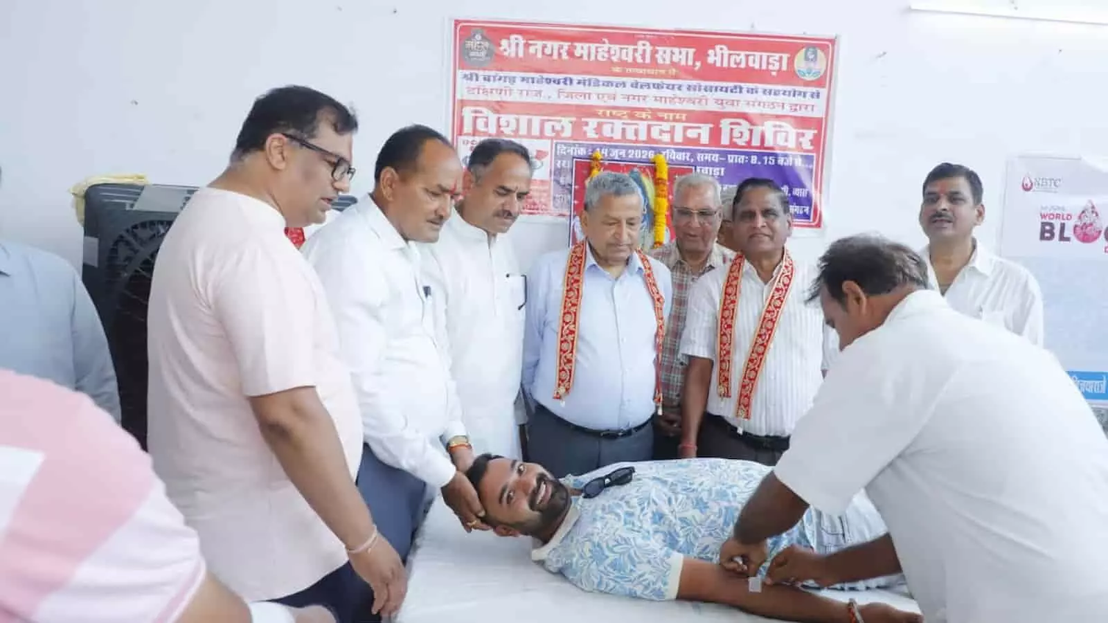 भीलवाड़ा के महेश छात्रावास परिसर में आयोजित रक्तदान शिविर के दौरान बेड पर लेटे युवक से रक्त संग्रहित करती मेडिकल टीम और खड़े लोग। भीलवाड़ा के महेश छात्रावास परिसर में आयोजित रक्तदान शिविर के दौरान बेड पर लेटे युवक से रक्त संग्रहित करती मेडिकल टीम और खड़े लोग।