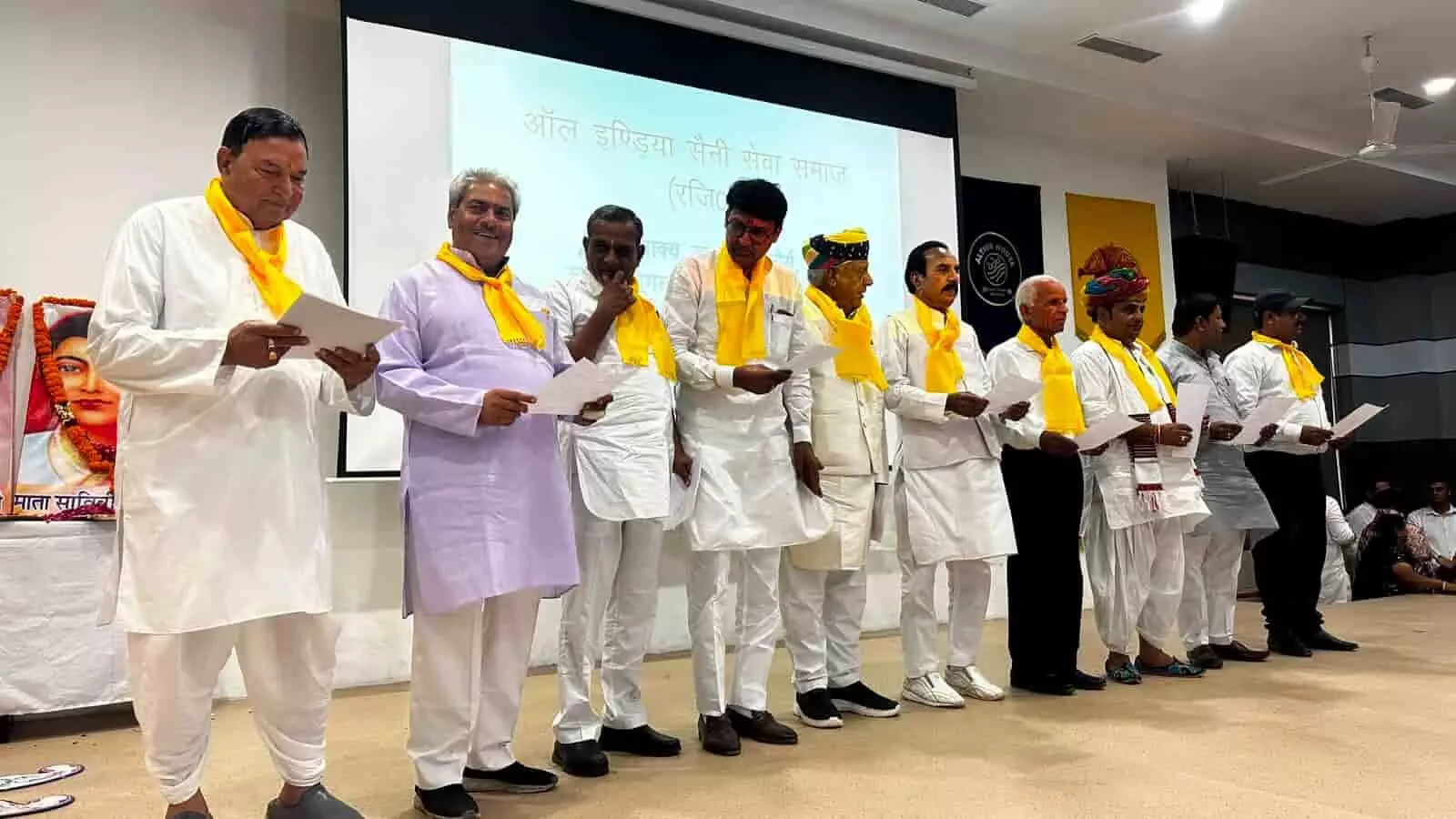 गुड़गांव के बैंकट हॉल में मंच पर खड़े होकर शपथ लेते ऑल इंडिया सैनी सेवा समाज के पदाधिकारी और सदस्य।