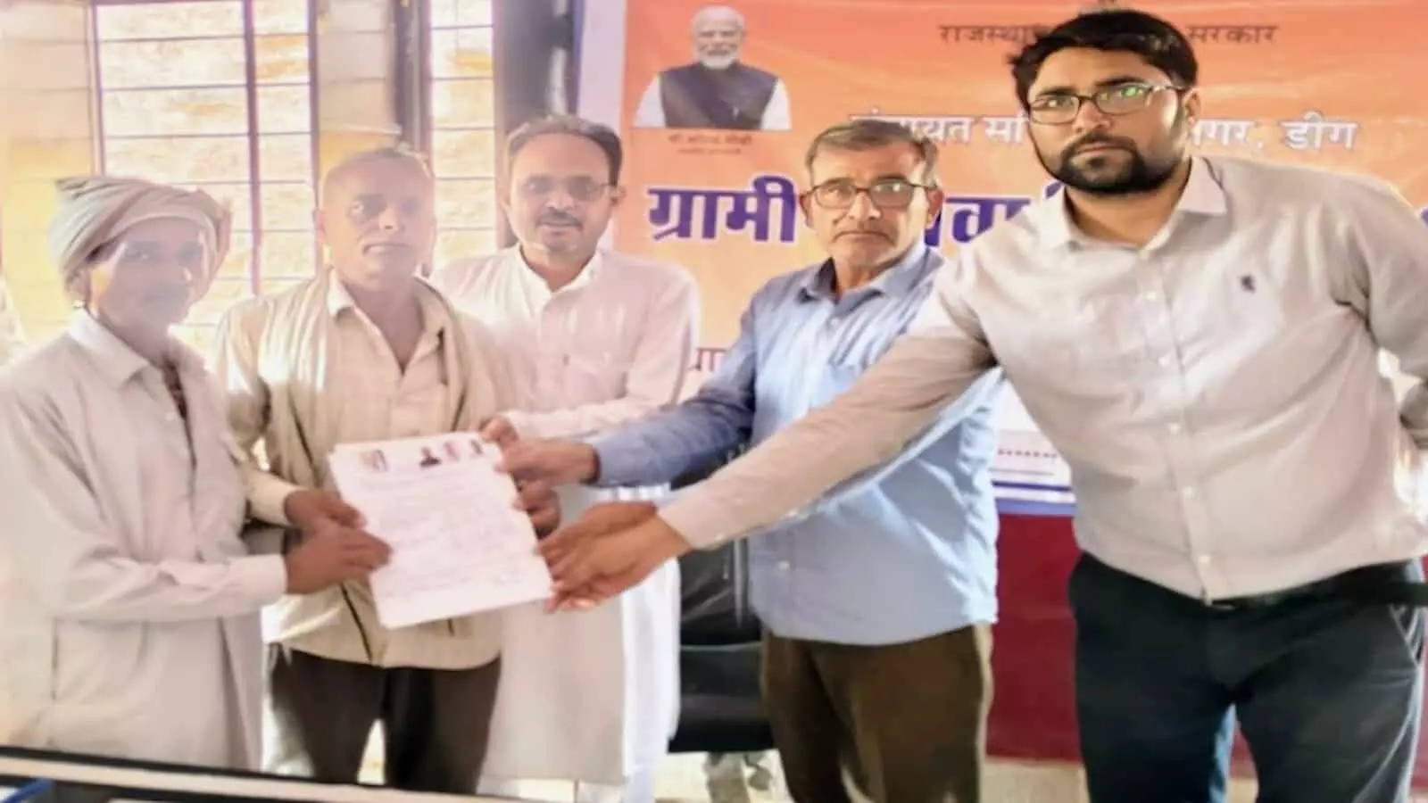 ग्रामीण सेवा शिविर में अधिकारियों से जमीन के कागजात लेते हुए दो ग्रामीण व्यक्ति ग्रामीण सेवा शिविर में अधिकारियों से जमीन के कागजात लेते हुए दो ग्रामीण व्यक्ति