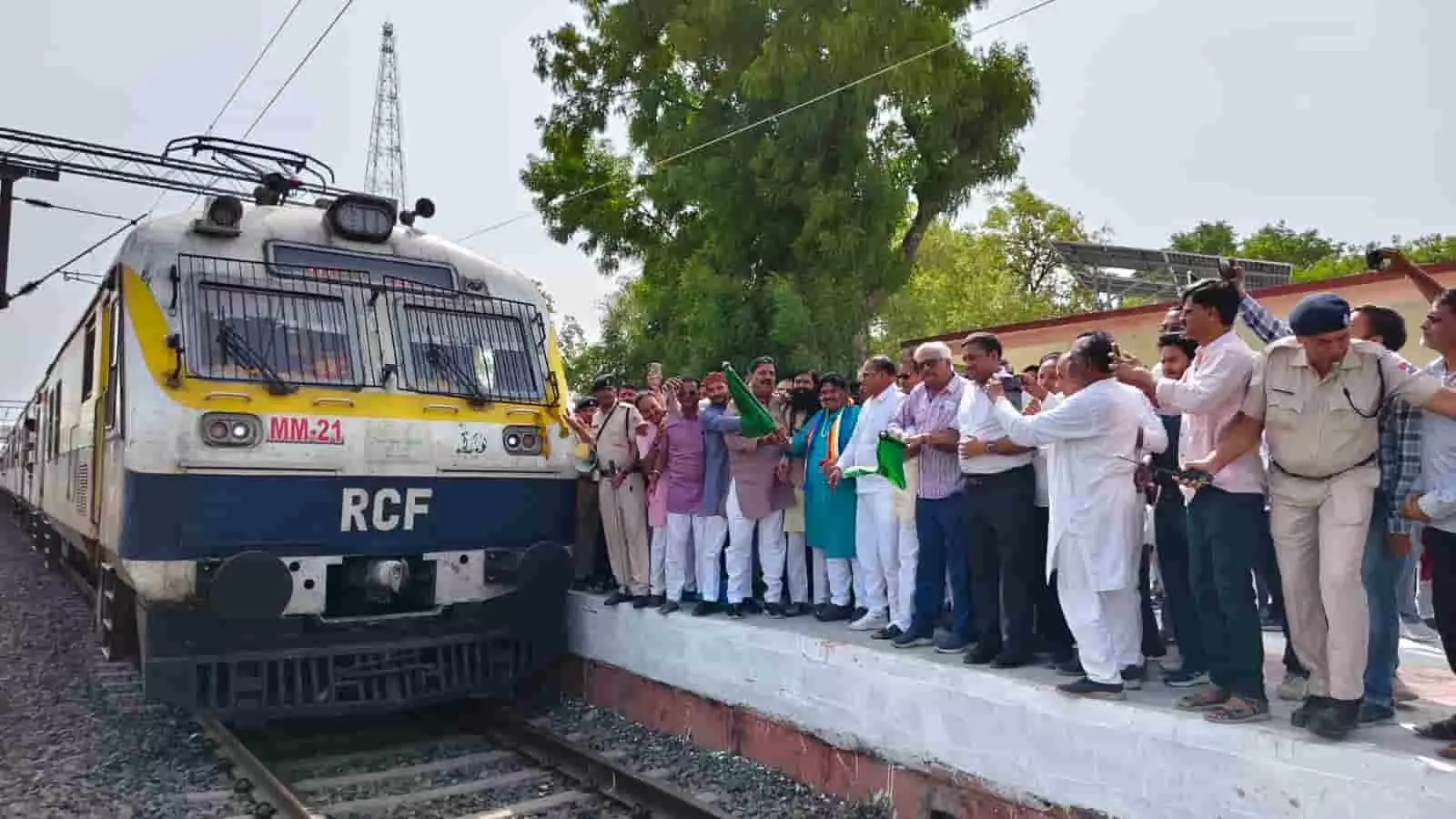 सफेद और नीले रंग की मेमू ट्रेन के सामने चौमहला रेलवे स्टेशन के प्लेटफॉर्म पर हरी झंडी दिखाते लोग। सफेद और नीले रंग की मेमू ट्रेन के सामने चौमहला रेलवे स्टेशन के प्लेटफॉर्म पर हरी झंडी दिखाते लोग।