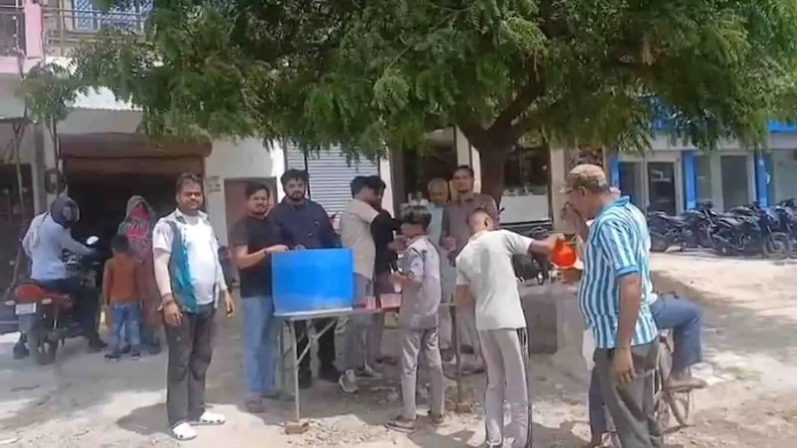 कानपुर देहात के संदलपुर में कटियार पॉली क्लीनिक के सामने राहगीरों को शरबत बांटते हुए लोग।