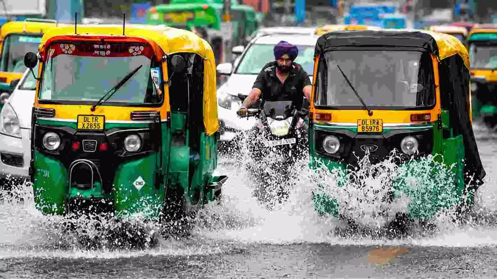दिल्ली की सड़कों पर तेज बारिश के दौरान चलते हुए ऑटो रिक्शा और वाहन। दिल्ली की सड़कों पर तेज बारिश के दौरान चलते हुए ऑटो रिक्शा और वाहन।
