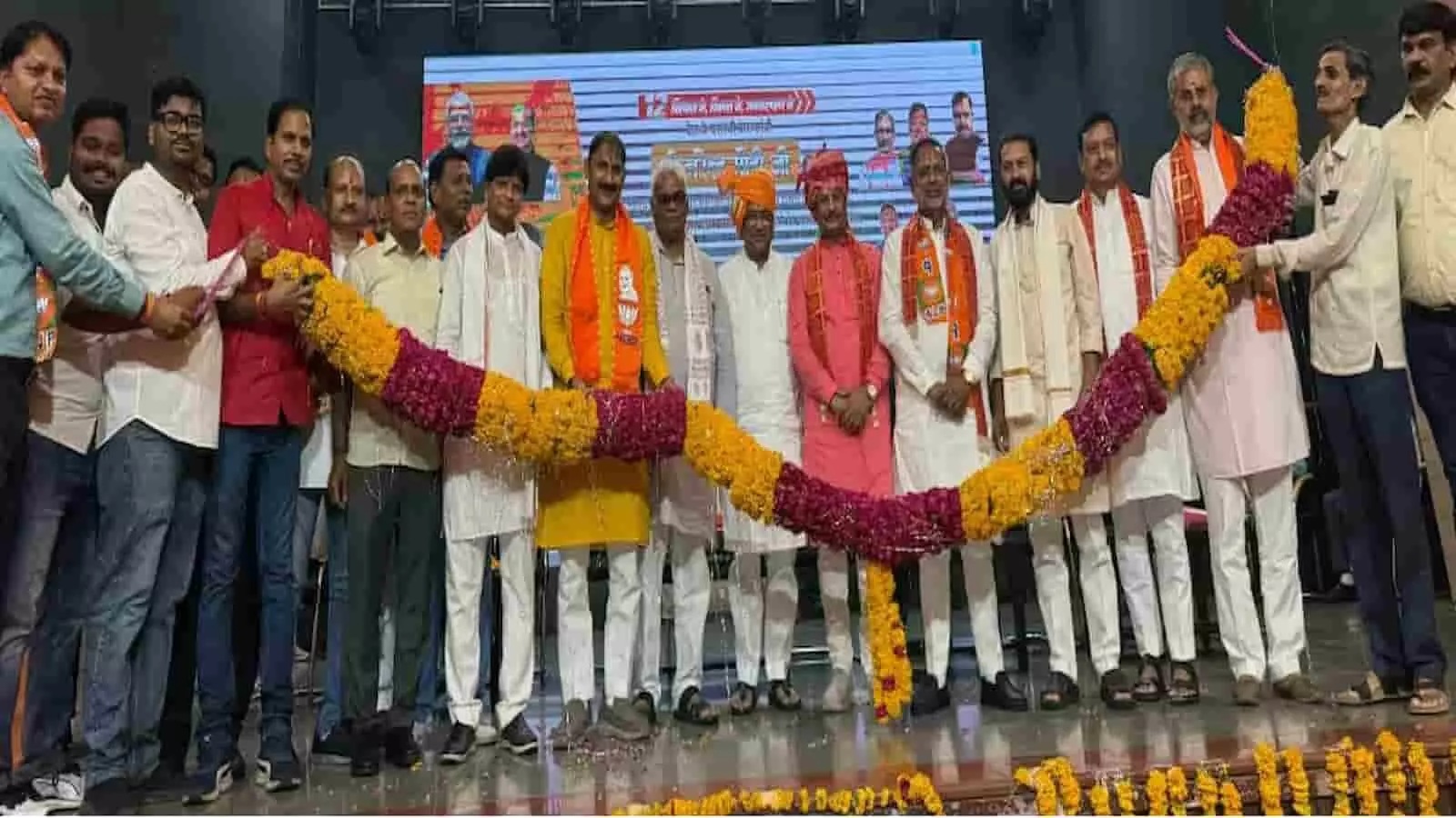 कोटा में आयोजित भाजपा के कार्यक्रम के दौरान मंच पर बड़ी फूलों की माला पकड़े हुए पार्टी नेता और कार्यकर्ता। कोटा में आयोजित भाजपा के कार्यक्रम के दौरान मंच पर बड़ी फूलों की माला पकड़े हुए पार्टी नेता और कार्यकर्ता।