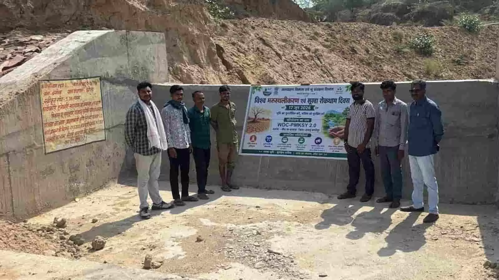 सवाई माधोपुर में नवनिर्मित जल संरक्षण ढांचे और बैनर के पास खड़े ग्रामीण और अधिकारी।