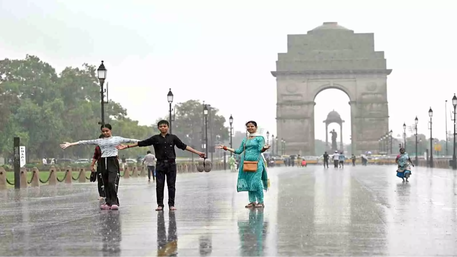 बारिश के दौरान इंडिया गेट के पास लोग मौसम का आनंद ले रहे हैं। बारिश के दौरान इंडिया गेट के पास लोग मौसम का आनंद ले रहे हैं।
