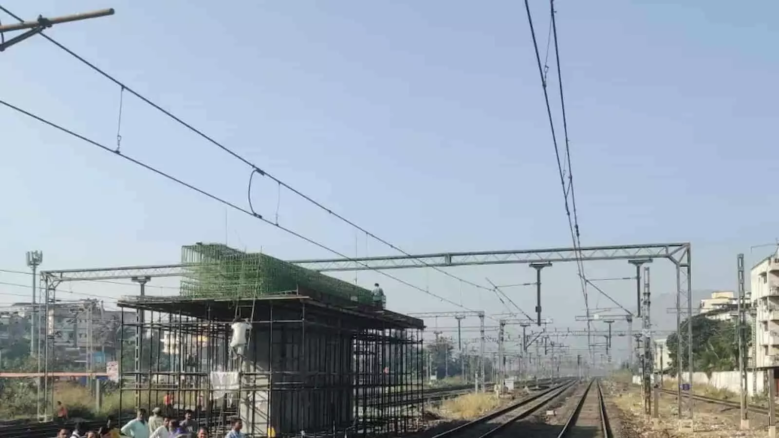 दिवा स्टेशन पर रेलवे ट्रैक के ऊपर निर्माणाधीन फुटओवर ब्रिज का ढांचा और काम करते मजदूर।
