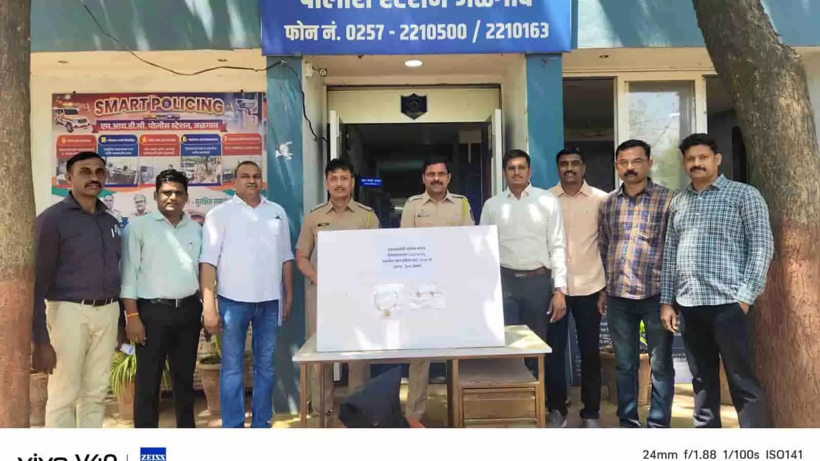 जलगांव एमआईडीसी पुलिस स्टेशन के बाहर सफेद प्रदर्शन बोर्ड के साथ खड़े पुलिस अधिकारी और जांच टीम के सदस्य।