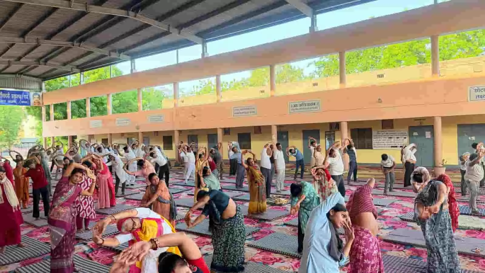 छोटीसादड़ी के विद्यालय परिसर में सामूहिक योगाभ्यास करते हुए लोग और योग प्रशिक्षक छोटीसादड़ी के विद्यालय परिसर में सामूहिक योगाभ्यास करते हुए लोग और योग प्रशिक्षक