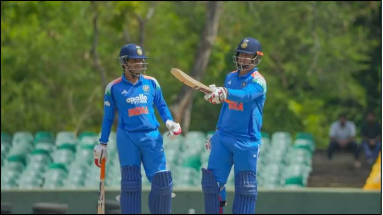 क्रिकेट मैदान पर नीली जर्सी और हेलमेट पहने दो भारतीय बल्लेबाज एक दूसरे को बधाई देते हुए। क्रिकेट मैदान पर नीली जर्सी और हेलमेट पहने दो भारतीय बल्लेबाज एक दूसरे को बधाई देते हुए।
