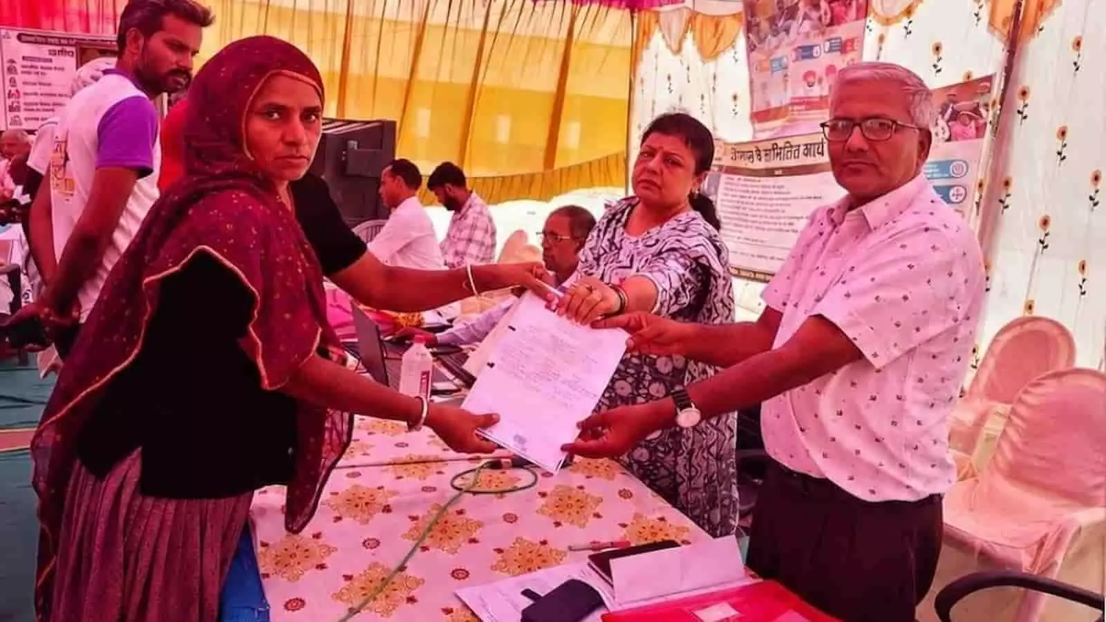 चित्तौड़गढ़ ग्रामीण सेवा शिविर में प्रशासनिक अधिकारियों द्वारा महिला लाभार्थी को दस्तावेज सौंपते हुए दृश्य।