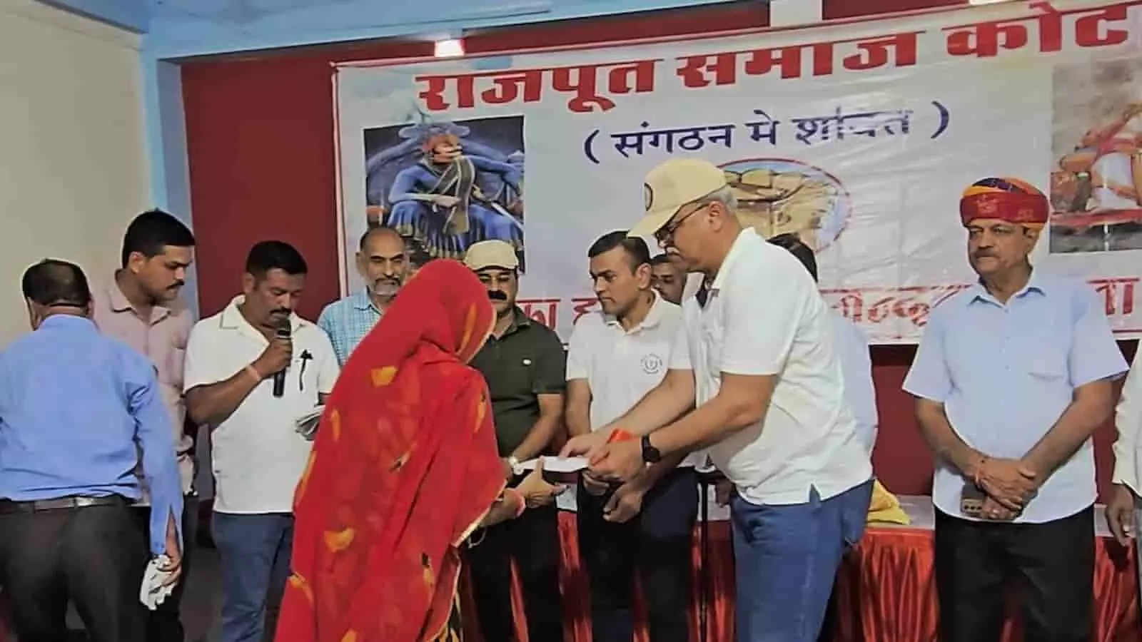 तस्वीर में राजपूत समाज के पदाधिकारी कोटा के चौहान भवन में सामाजिक पेंशन योजना के तहत महिला लाभार्थी को सहायता राशि प्रदान करते हुए दिख रहे हैं