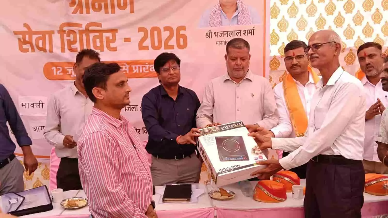 तस्वीर में मावली के अधिकारी ग्रामीण सेवा शिविर में लाभार्थियों को सामग्री वितरित करते दिख रहे हैं। तस्वीर में मावली के अधिकारी ग्रामीण सेवा शिविर में लाभार्थियों को सामग्री वितरित करते दिख रहे हैं।