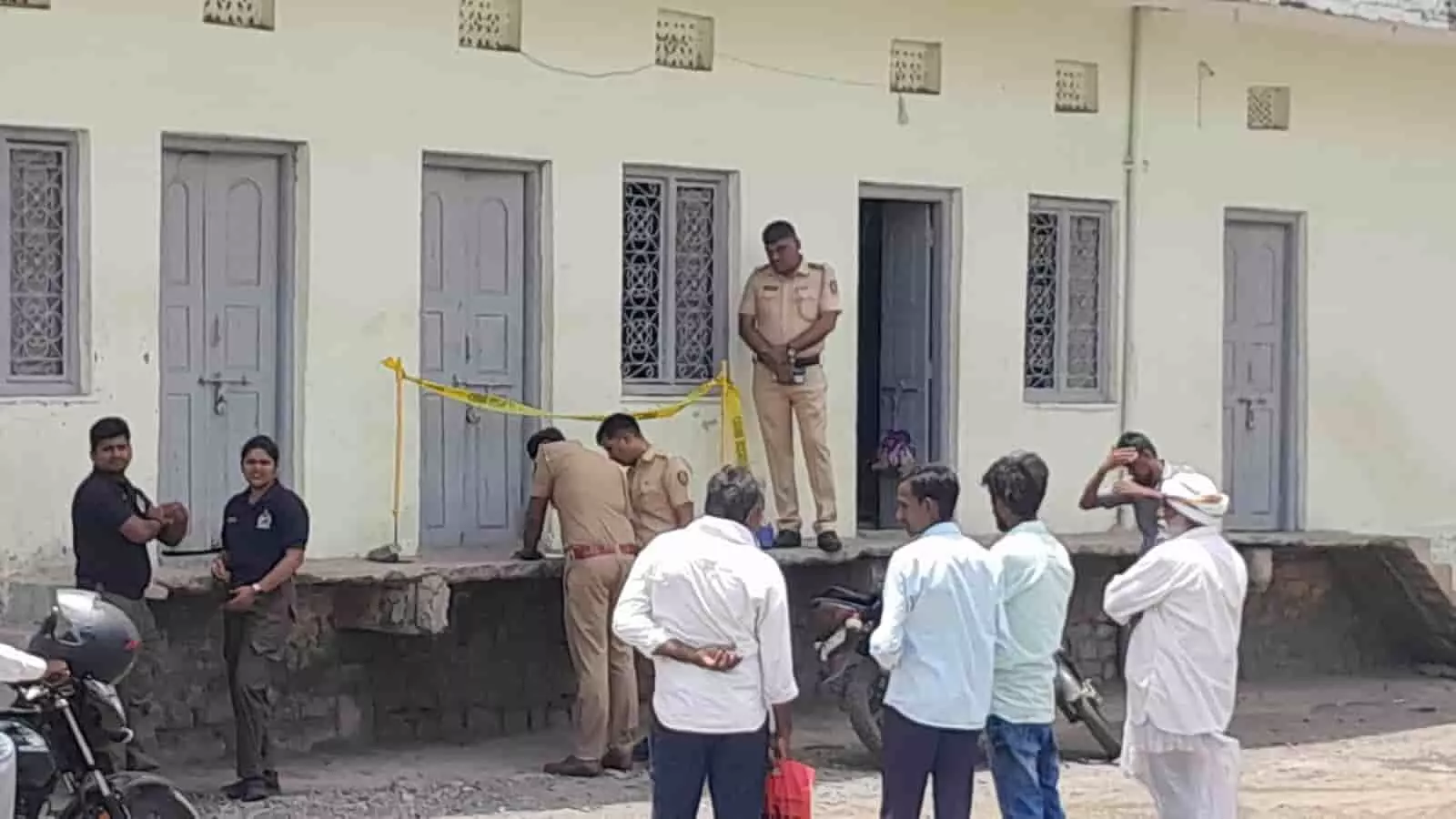 उदगीर में अपराध स्थल के बाहर जांच करते पुलिसकर्मी और खड़े हुए स्थानीय लोग।