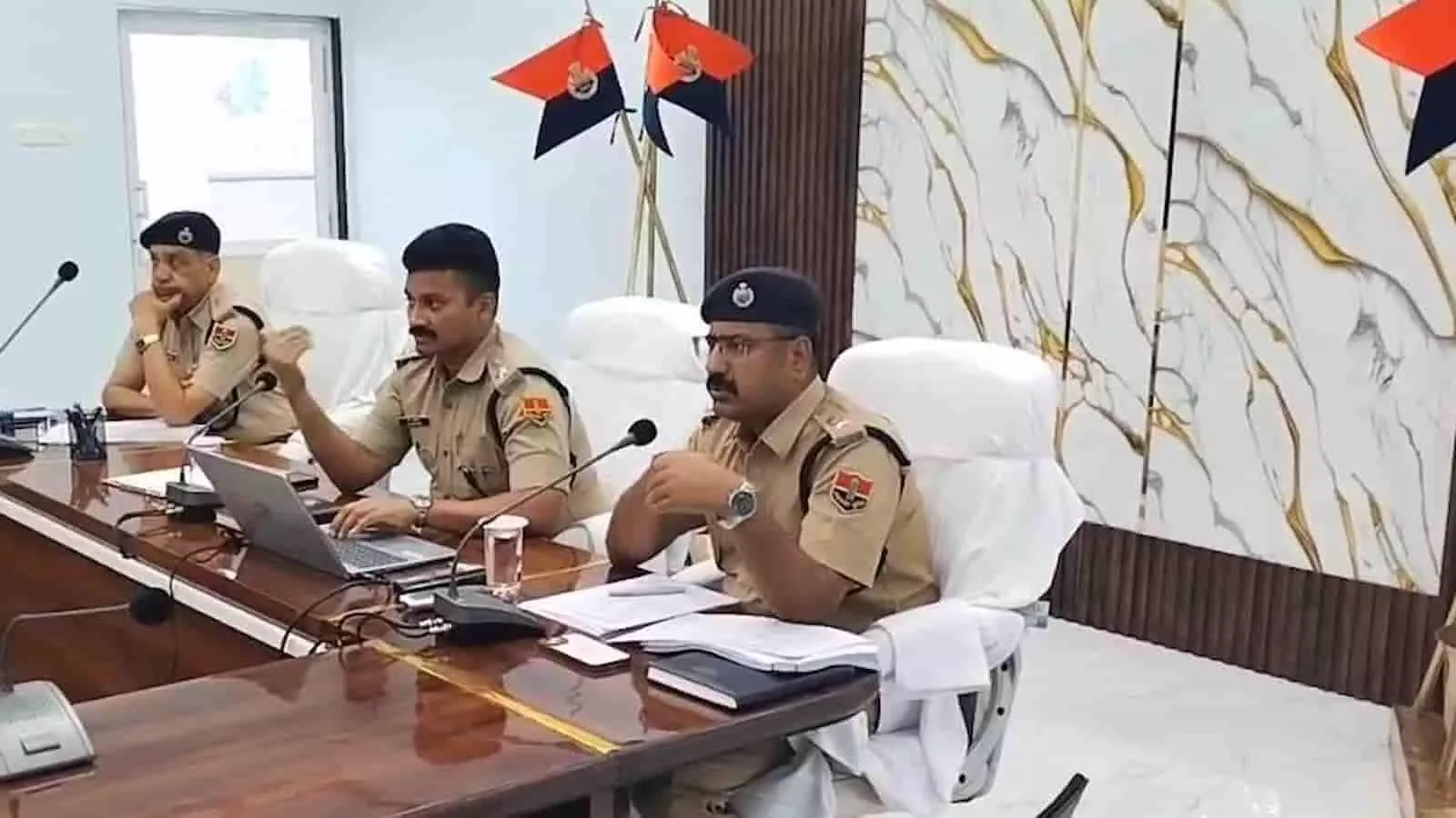 कॉन्फ्रेंस हॉल में बैठक के दौरान मेज पर रखे लैपटॉप और माइक के सामने बैठे पुलिस अधिकारी कॉन्फ्रेंस हॉल में बैठक के दौरान मेज पर रखे लैपटॉप और माइक के सामने बैठे पुलिस अधिकारी