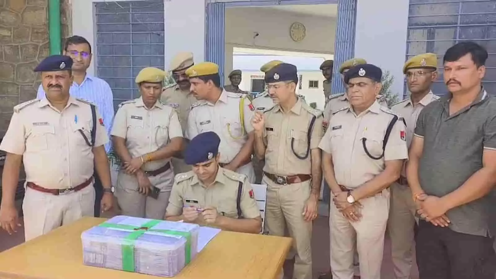 मेज पर बरामद नकदी और कागजात के साथ खड़े राजसमंद पुलिस के अधिकारी और गिरफ्तार आरोपी। मेज पर बरामद नकदी और कागजात के साथ खड़े राजसमंद पुलिस के अधिकारी और गिरफ्तार आरोपी।