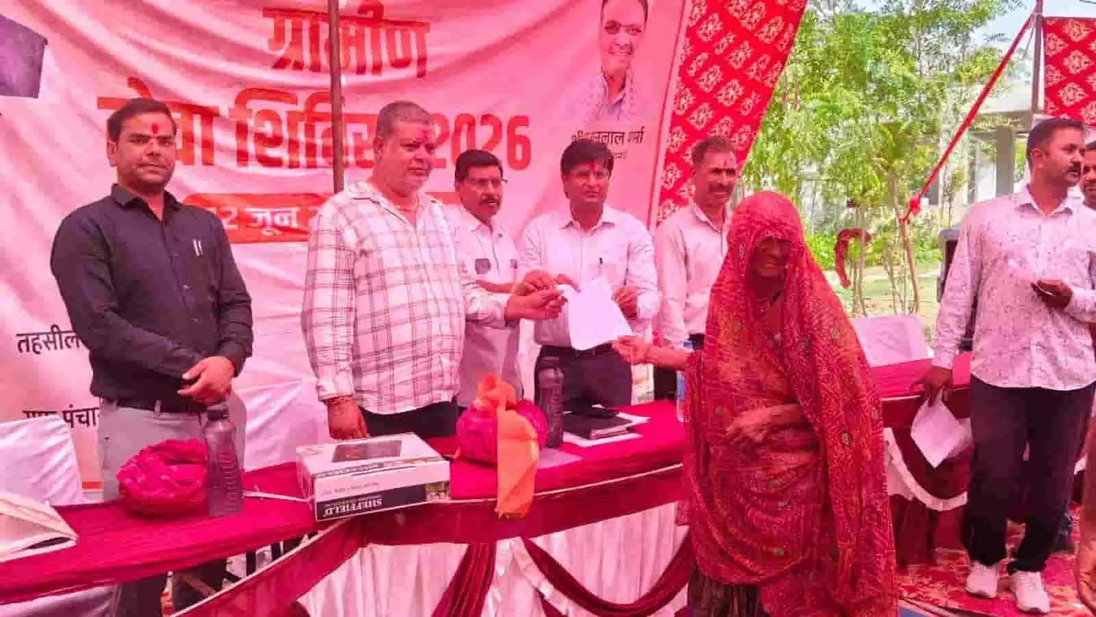 मावली के ग्रामीण सेवा शिविर में अधिकारी मंच पर एक ग्रामीण महिला को सरकारी दस्तावेज और किट सौंप रहे हैं। मावली के ग्रामीण सेवा शिविर में अधिकारी मंच पर एक ग्रामीण महिला को सरकारी दस्तावेज और किट सौंप रहे हैं।