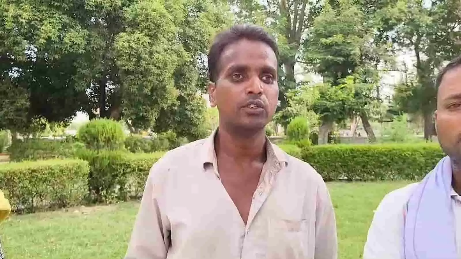 हरे-भरे पेड़ों के सामने खड़े होकर बात करते हुए मनोज भील का दृश्य। हरे-भरे पेड़ों के सामने खड़े होकर बात करते हुए मनोज भील का दृश्य।