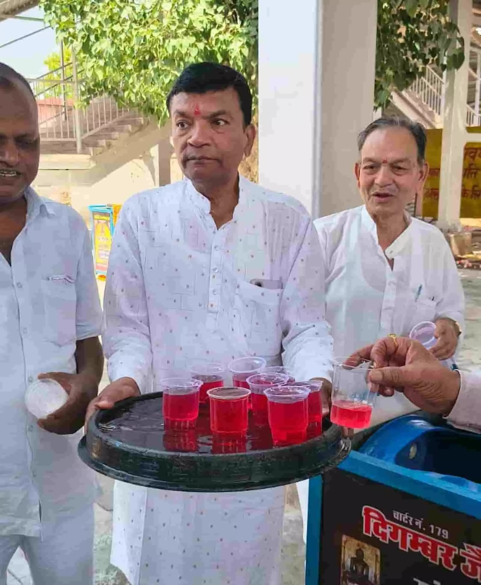 रेलवे स्टेशन पर ट्रे में शरबत के गिलास लिए खड़ा सफेद कुर्ते में एक व्यक्ति। रेलवे स्टेशन पर ट्रे में शरबत के गिलास लिए खड़ा सफेद कुर्ते में एक व्यक्ति।
