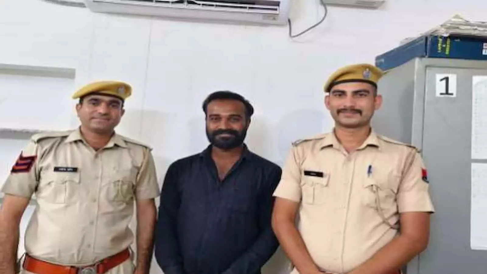 साइबर पुलिस थाने के कार्यालय में दो पुलिसकर्मियों के बीच खड़ा एक व्यक्ति। साइबर पुलिस थाने के कार्यालय में दो पुलिसकर्मियों के बीच खड़ा एक व्यक्ति।