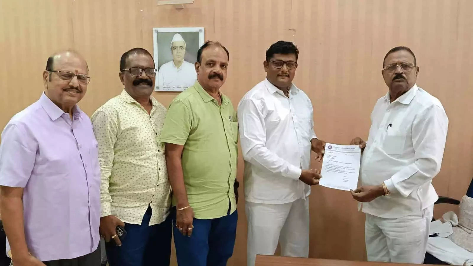कमरे में पांच पुरुष खड़े होकर सफेद कागज या नियुक्ति पत्र दिखाते हुए। कमरे में पांच पुरुष खड़े होकर सफेद कागज या नियुक्ति पत्र दिखाते हुए।