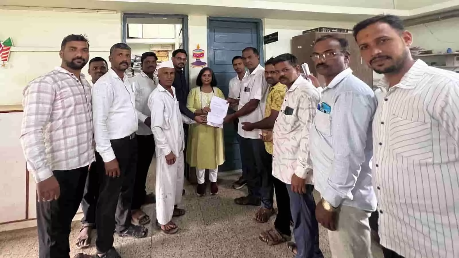 कार्यालय में कागज का ज्ञापन पत्र थामे ग्रामीण और महिला प्रतिनिधि समूह फोटो के दौरान।