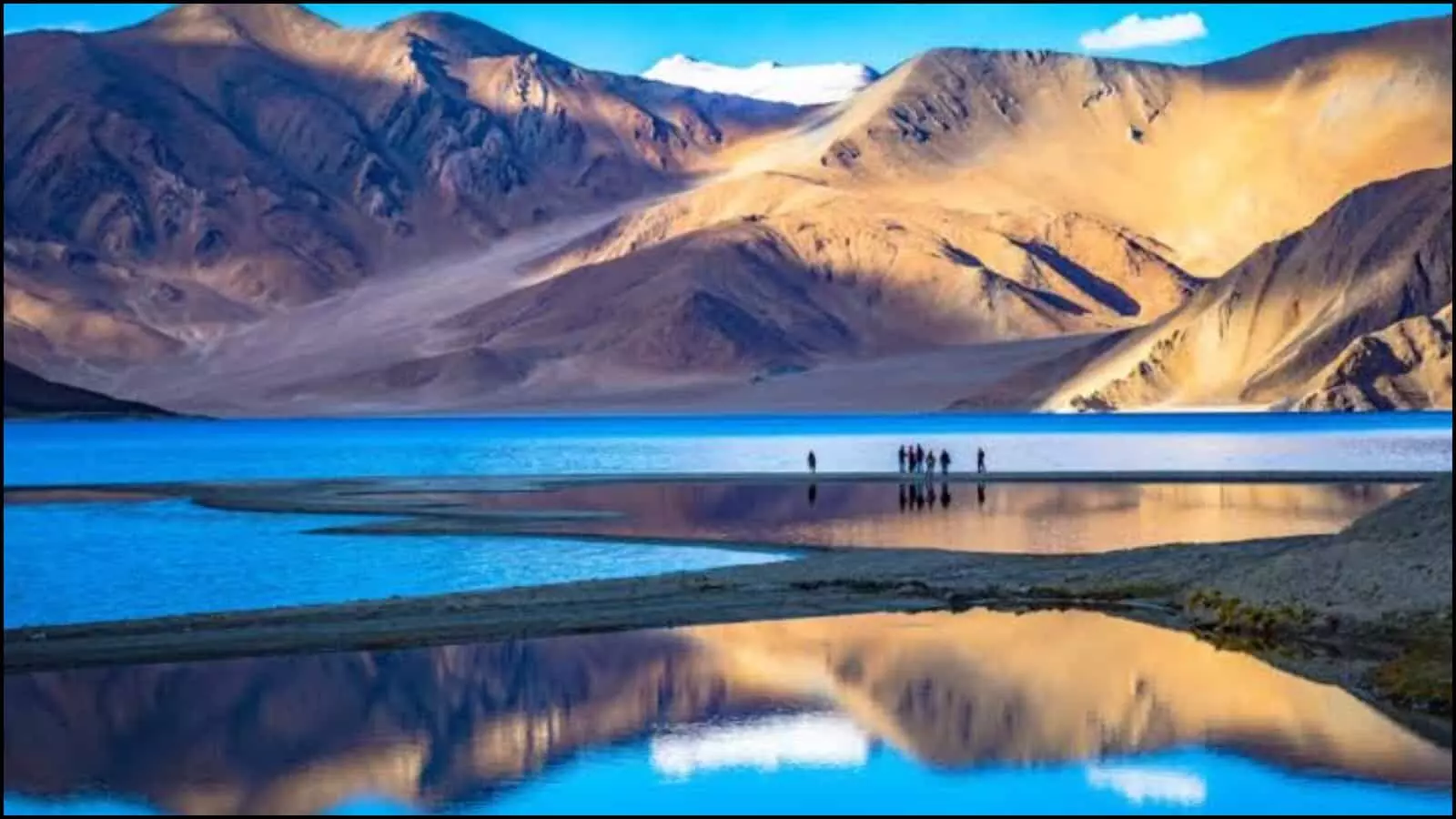 पर्वतों और नीली झील का प्राकृतिक दृश्य पर्यटकों के साथ भारत में पर्यटन बुनियादी ढांचा विकास के संदर्भ में।