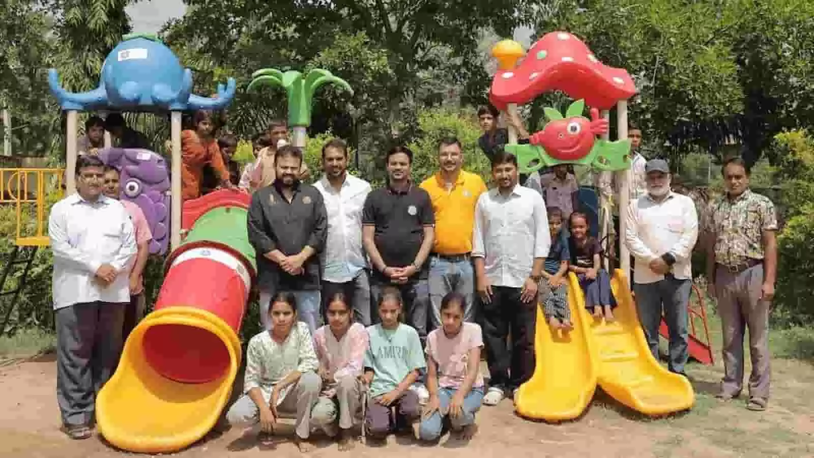 स्कूल के फन जोन में बच्चों के झूले के पास खड़े अतिथि और शिक्षक।