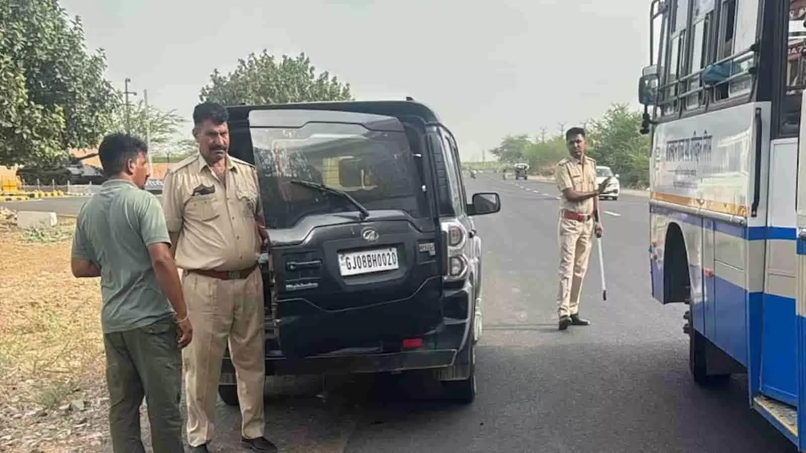 सड़क पर पुलिस कर्मी एक खड़ी कार की जांच कर रहे हैं।