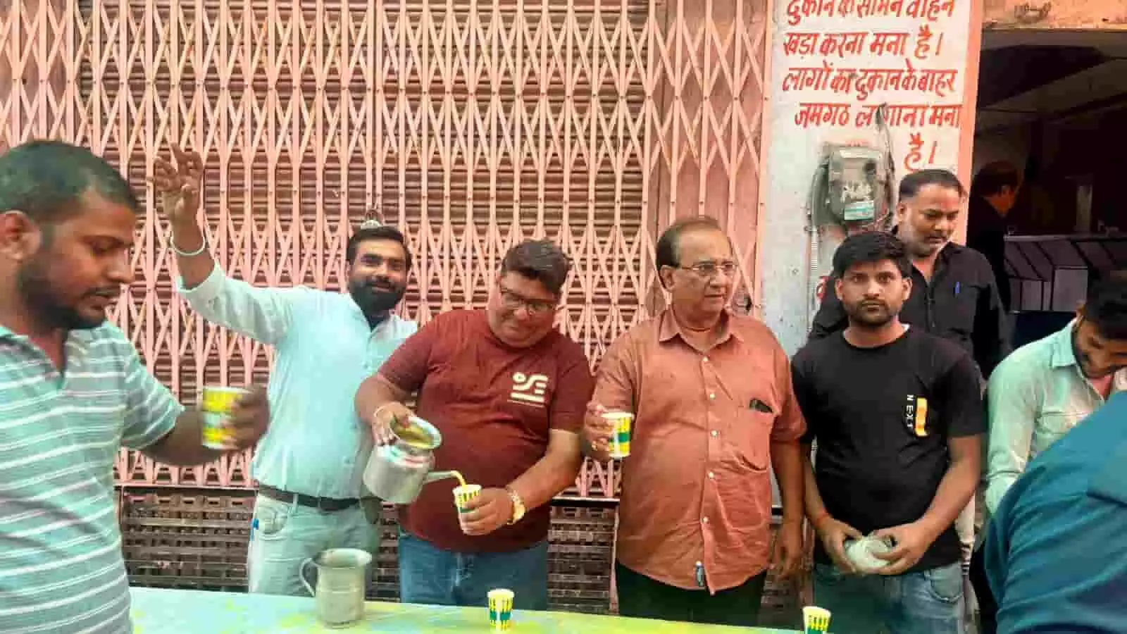 : बाजार में मेज के पीछे खड़े पुरुषों द्वारा कपों में मैंगो शेक भरने का दृश्य। : बाजार में मेज के पीछे खड़े पुरुषों द्वारा कपों में मैंगो शेक भरने का दृश्य।