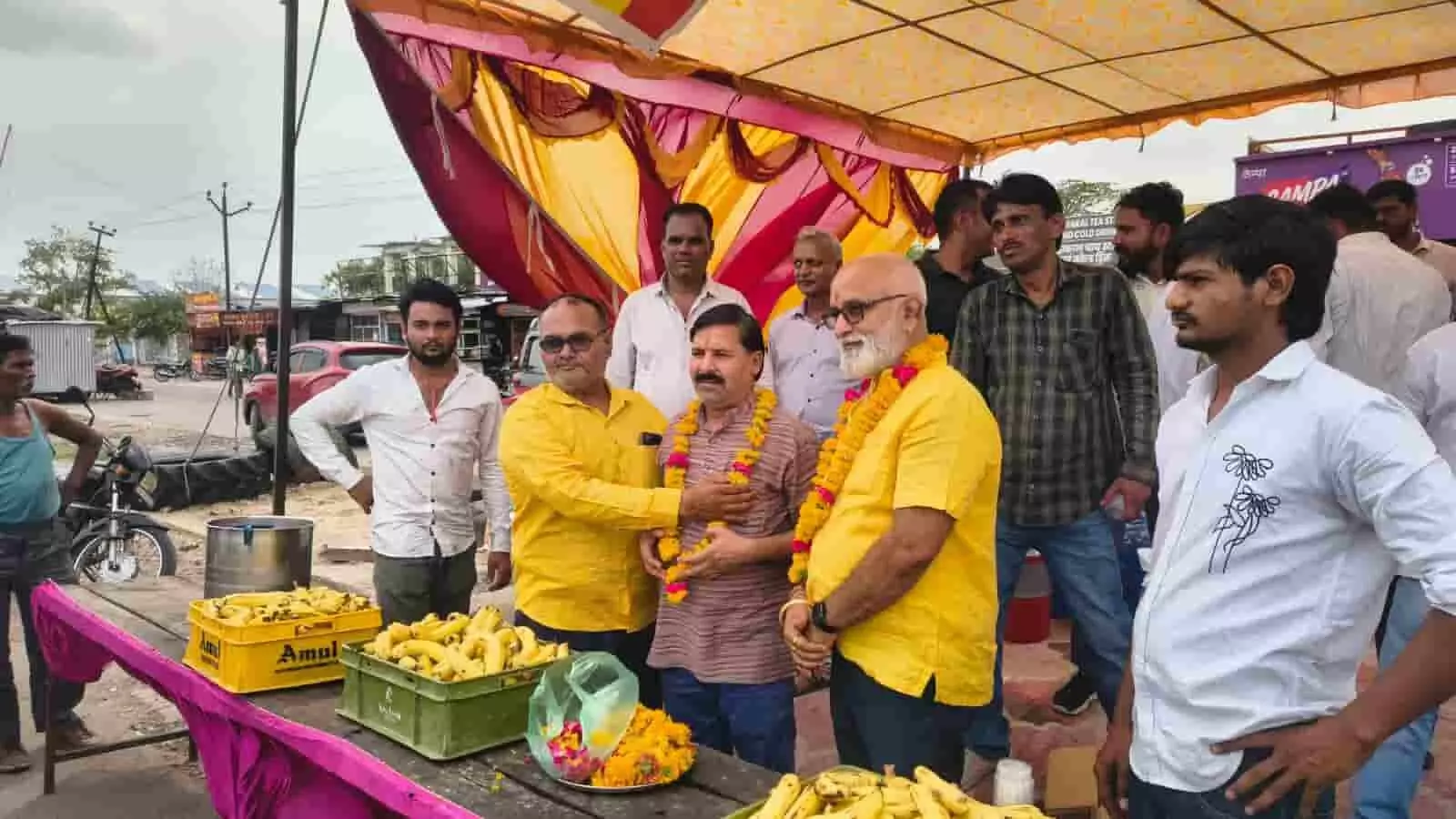 गौमती चौराहा कोटा पर सेवा कार्यक्रम के दौरान राहगीरों को केला वितरित करते लोग।
