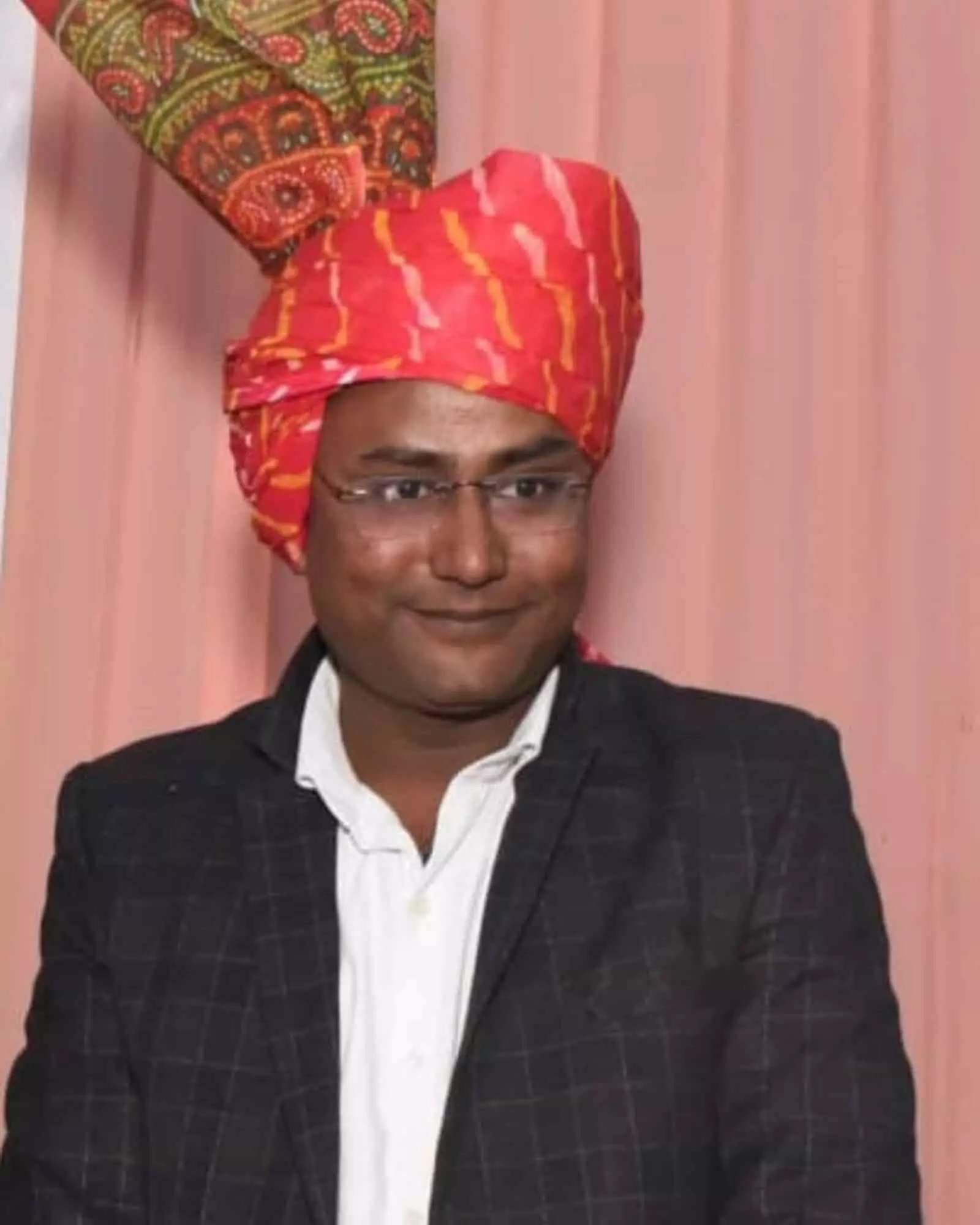 लाल पगड़ी और काले ब्लेजर में सौरभ गर्ग मुस्कुराते हुए दिखाई दे रहे हैं।