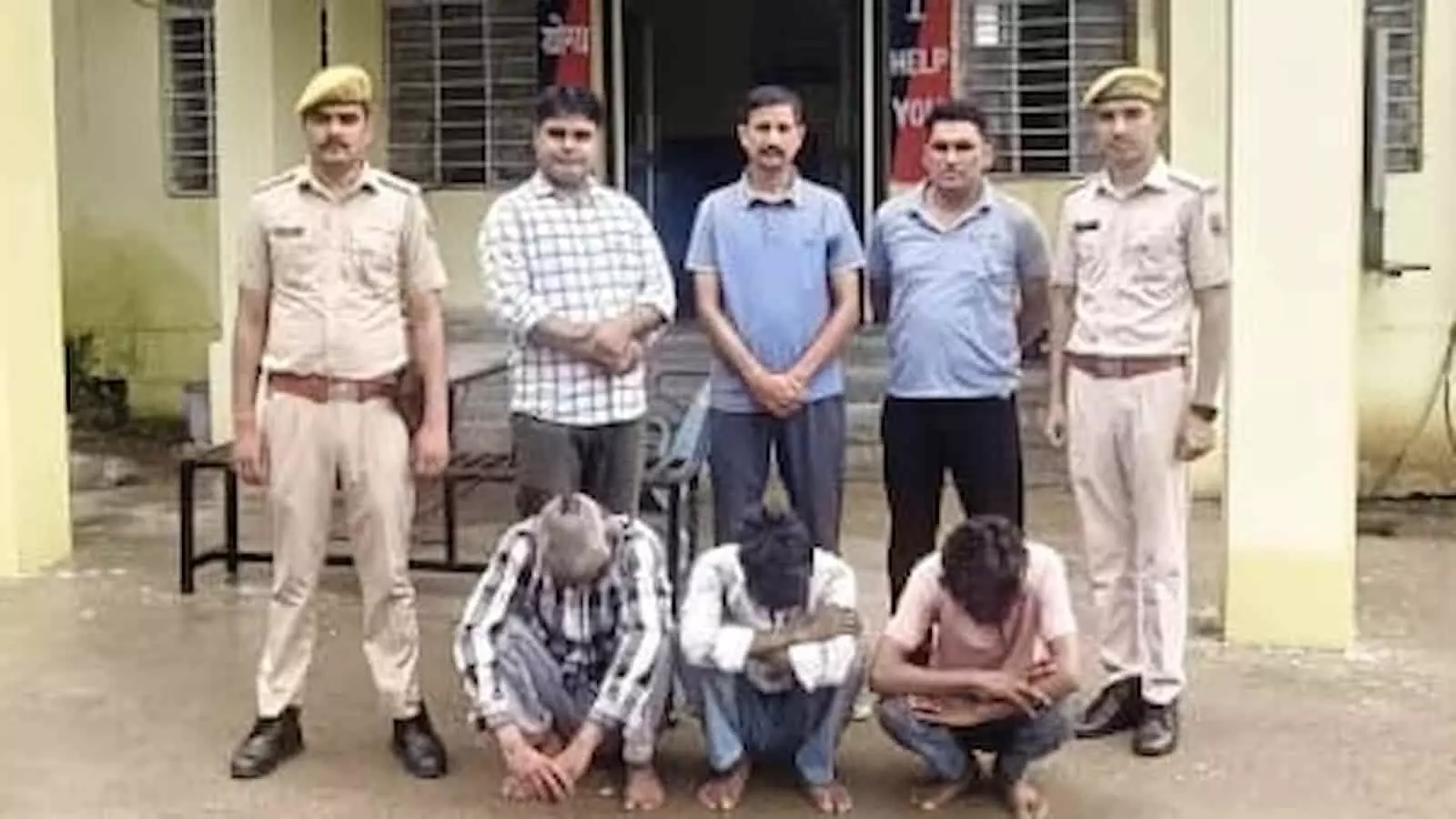 पुलिस स्टेशन के बाहर खड़े पुलिसकर्मी और हिरासत में लिए गए तीन आरोपी।