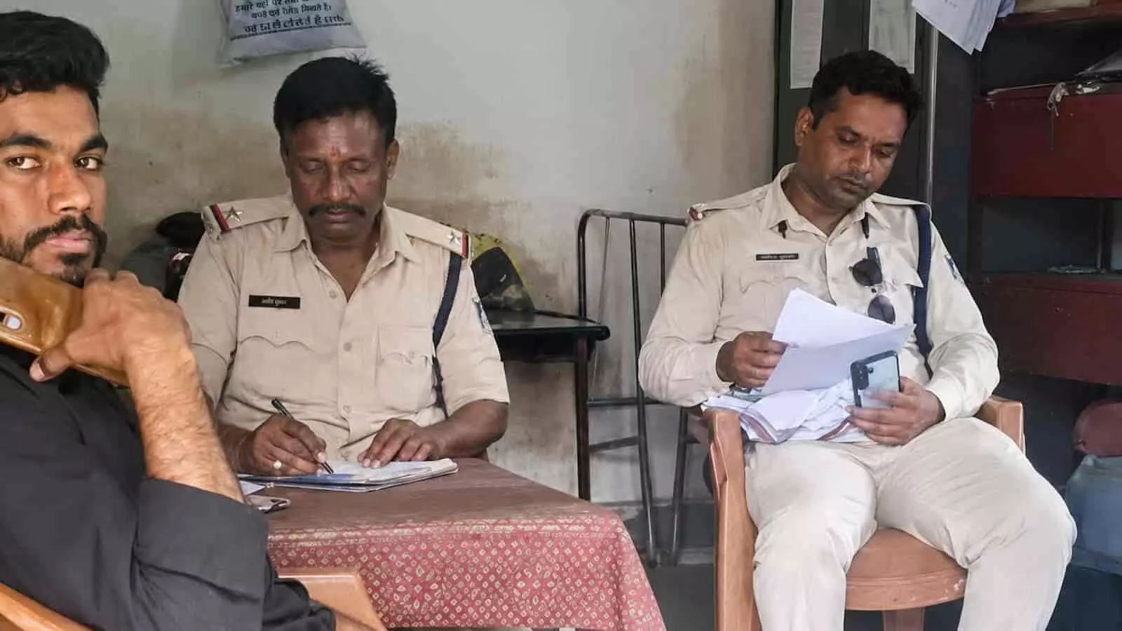 पुलिस चौकी में बैठे पुलिसकर्मी कागजात देखते हुए कानूनी कार्रवाई की जांच कर रहे हैं। पुलिस चौकी में बैठे पुलिसकर्मी कागजात देखते हुए कानूनी कार्रवाई की जांच कर रहे हैं।