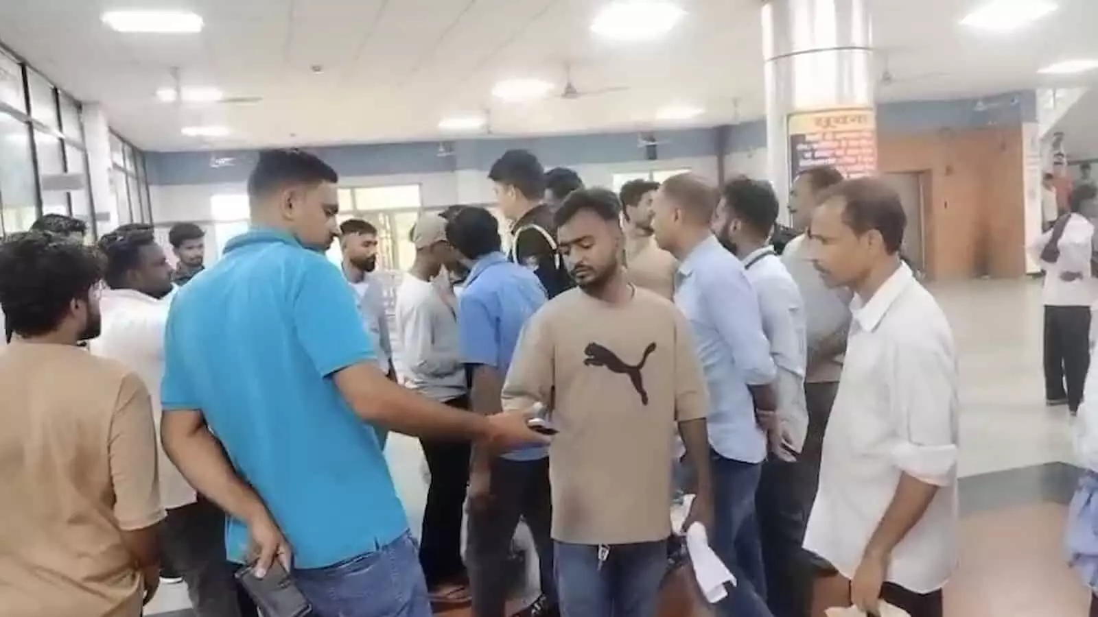 अस्पताल के भीतर हॉल में खड़े लोगों और तीमारदारों की भीड़ का दृश्य। अस्पताल के भीतर हॉल में खड़े लोगों और तीमारदारों की भीड़ का दृश्य।