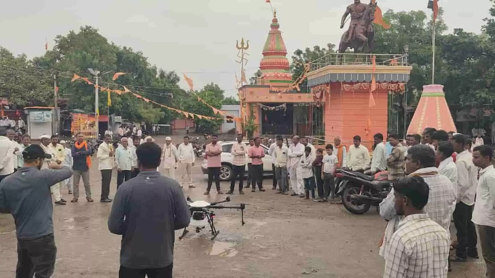 तस्वीर में मंदिर परिसर के सामने खड़े लोग कृषि ड्रोन का प्रदर्शन देखते हुए। तस्वीर में मंदिर परिसर के सामने खड़े लोग कृषि ड्रोन का प्रदर्शन देखते हुए।