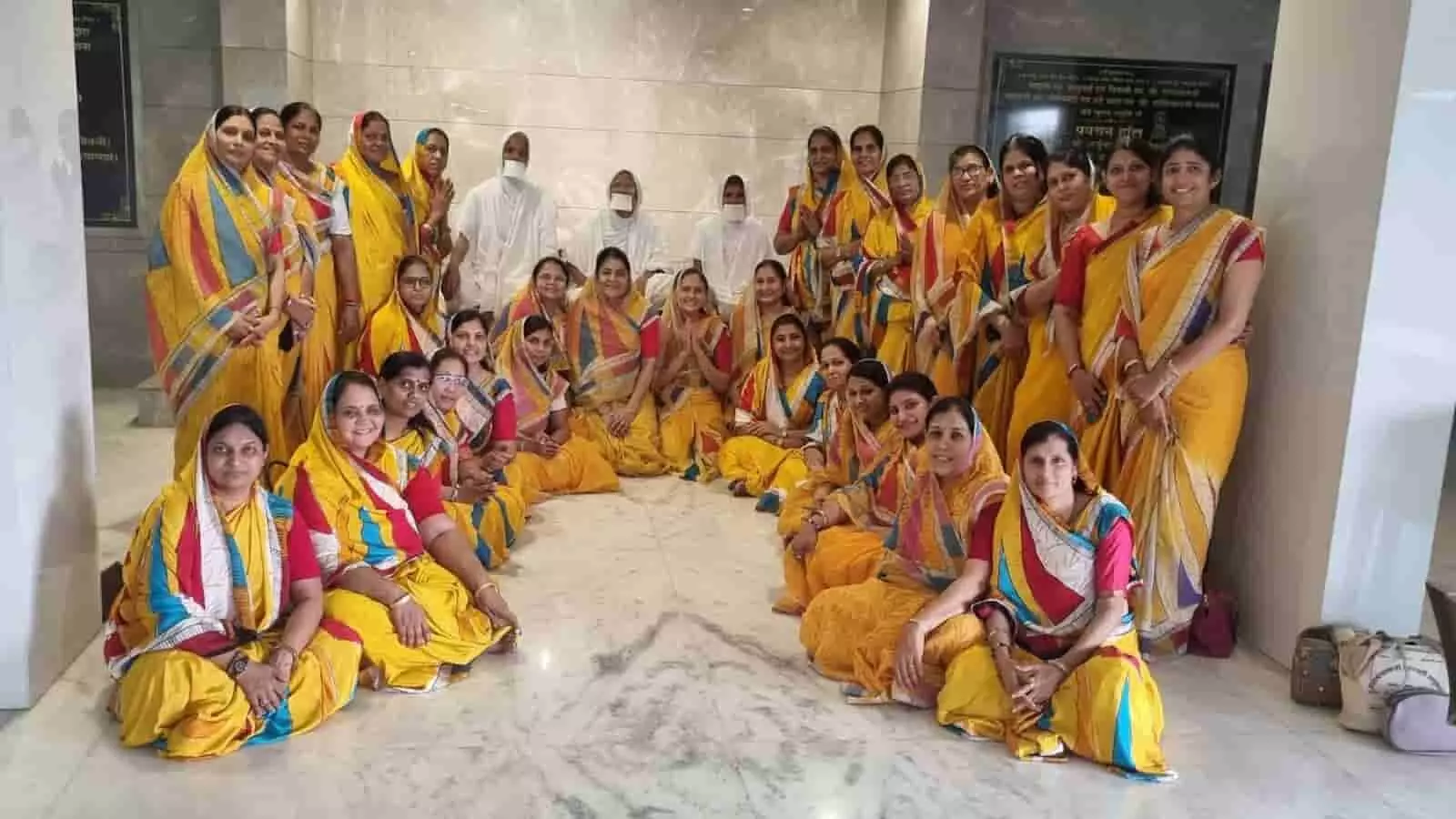 तस्वीर में पीले परिधान में सजी जैन महिला मंडल की सदस्य पनवेल में बैठक के दौरान समूह में बैठी हैं।