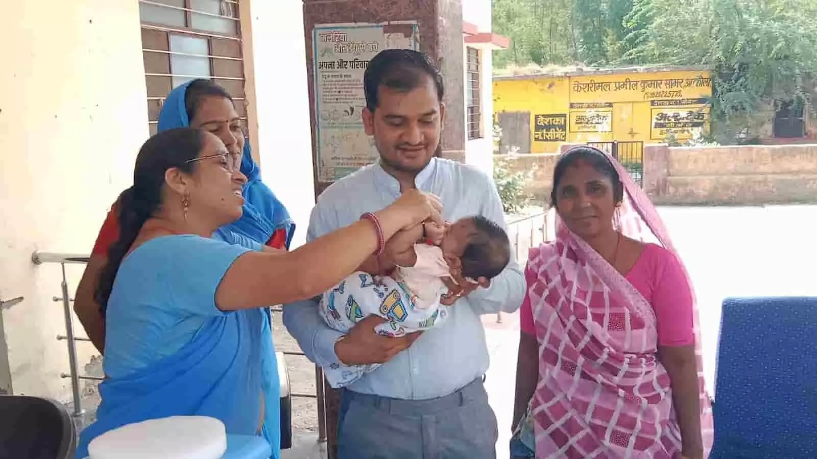 आकोला स्वास्थ्य केंद्र में बच्चे को पोलियो ड्रॉप पिलाती स्वास्थ्य कर्मी महिला की तस्वीर।