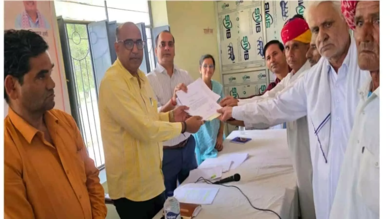 राजस्व अधिकारी किशनगढ़ रेनवाल में आवेदकों को भूमि विभाजन के दस्तावेज सौंप रहे हैं।