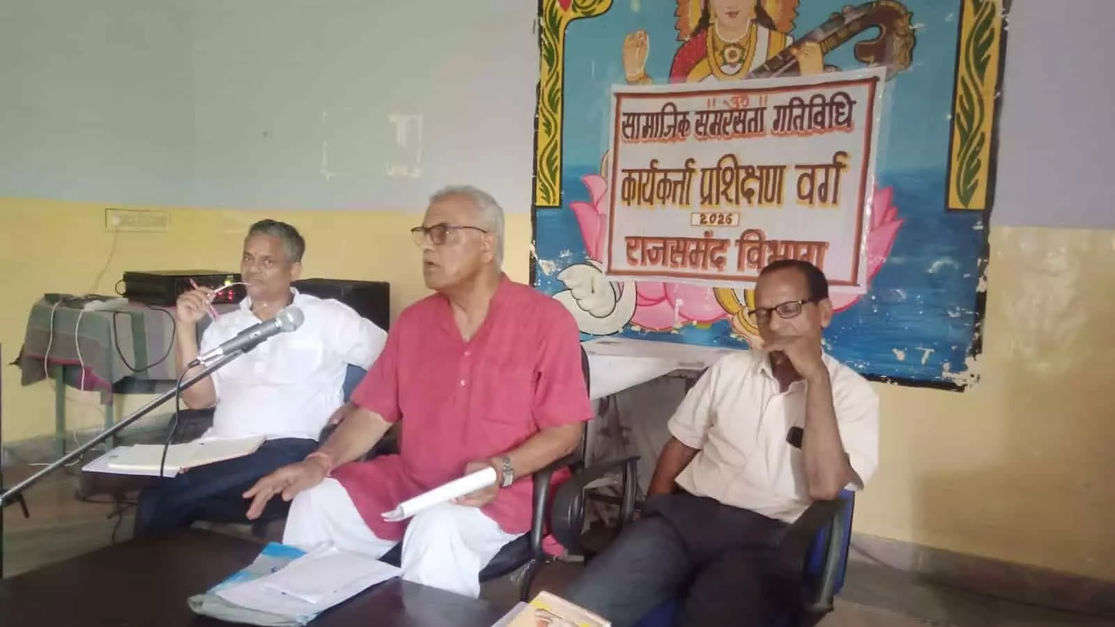 प्रशिक्षण वर्ग के मंच पर बैठे पदाधिकारी और पृष्ठभूमि में लगा सामाजिक समरसता गतिविधि का बैनर।