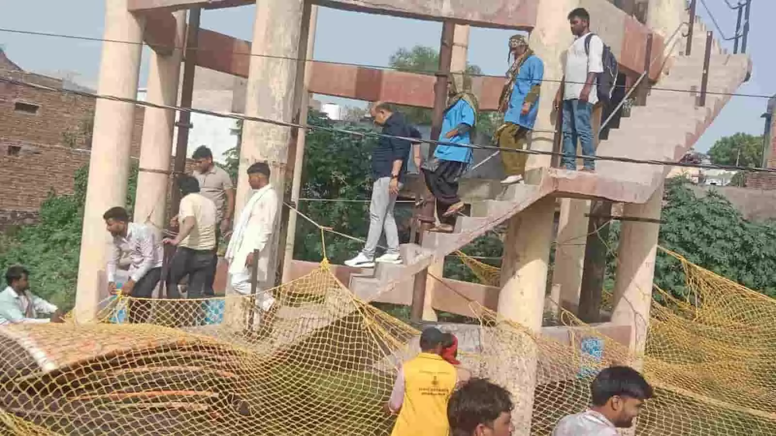 पानी की टंकी की सीढ़ियों से नीचे उतरतीं महिलाएं और मैदान में सुरक्षा के लिए लगा पीला जाल। पानी की टंकी की सीढ़ियों से नीचे उतरतीं महिलाएं और मैदान में सुरक्षा के लिए लगा पीला जाल।