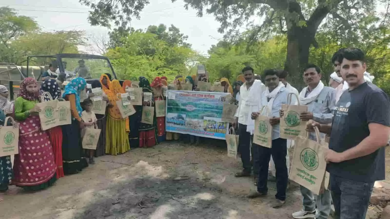 तस्वीर में रणथम्भौर बाघ रक्षक कार्यक्रम के दौरान ग्रामीण और वन कर्मी जूट बैग पकड़े हुए खड़े हैं।