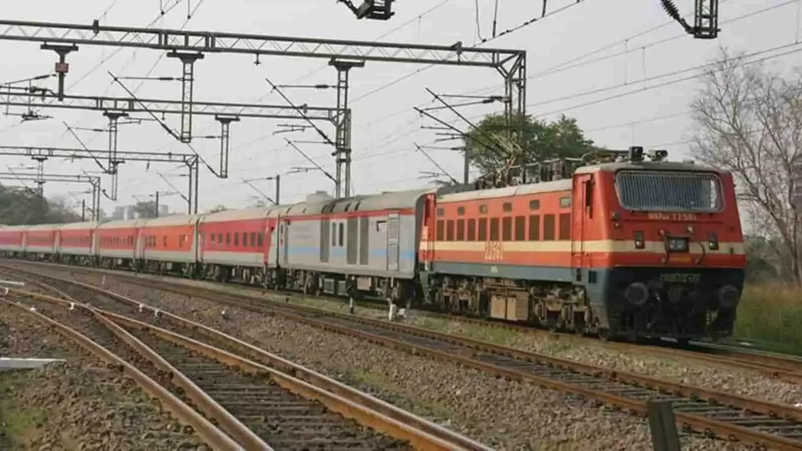 पटरी पर चलती हुई भारतीय रेलवे की एक ट्रेन तस्वीर में दिख रही है। पटरी पर चलती हुई भारतीय रेलवे की एक ट्रेन तस्वीर में दिख रही है।