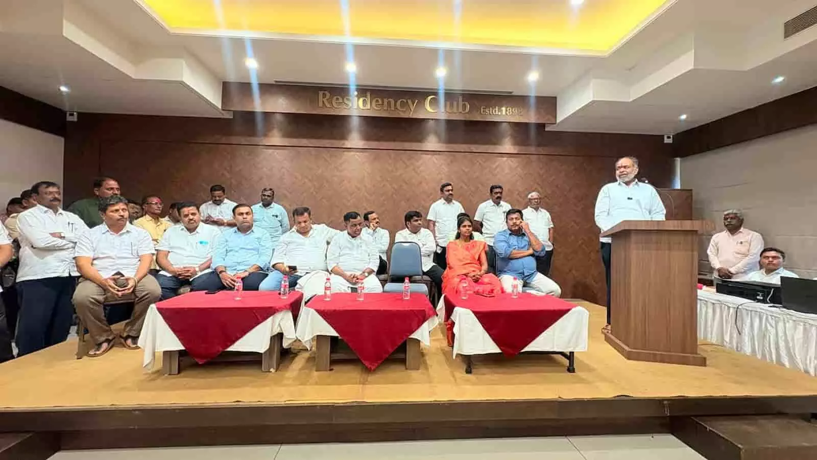 तस्वीर में मंच पर वक्ता और बैठे पदाधिकारी कोल्हापुर के रेसिडेंसी क्लब सभागार में दिखाई दे रहे हैं।B