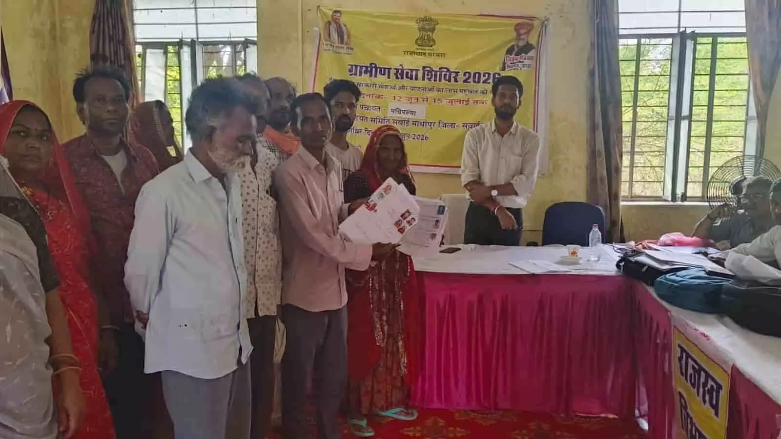 ग्रामीण सेवा शिविर में राजस्व अधिकारियों के सामने दस्तावेज लिए खड़े ग्रामीण और अधिकारी।