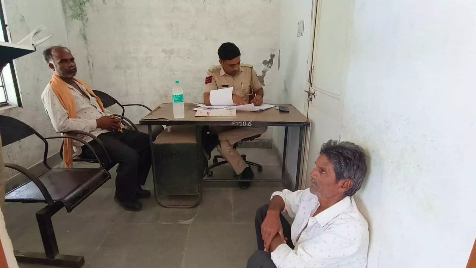 तस्वीर में कोटड़ी पुलिस थाने के अंदर कागजी कार्रवाई करते पुलिसकर्मी और बैठे हुए ग्रामीण दिख रहे हैं। तस्वीर में कोटड़ी पुलिस थाने के अंदर कागजी कार्रवाई करते पुलिसकर्मी और बैठे हुए ग्रामीण दिख रहे हैं।