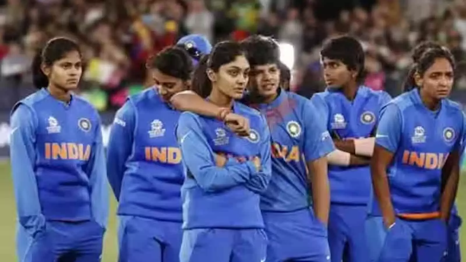 क्रिकेट स्टेडियम के मैदान पर नीली जर्सी पहने खड़ी भारतीय महिला क्रिकेट टीम की खिलाड़ी।