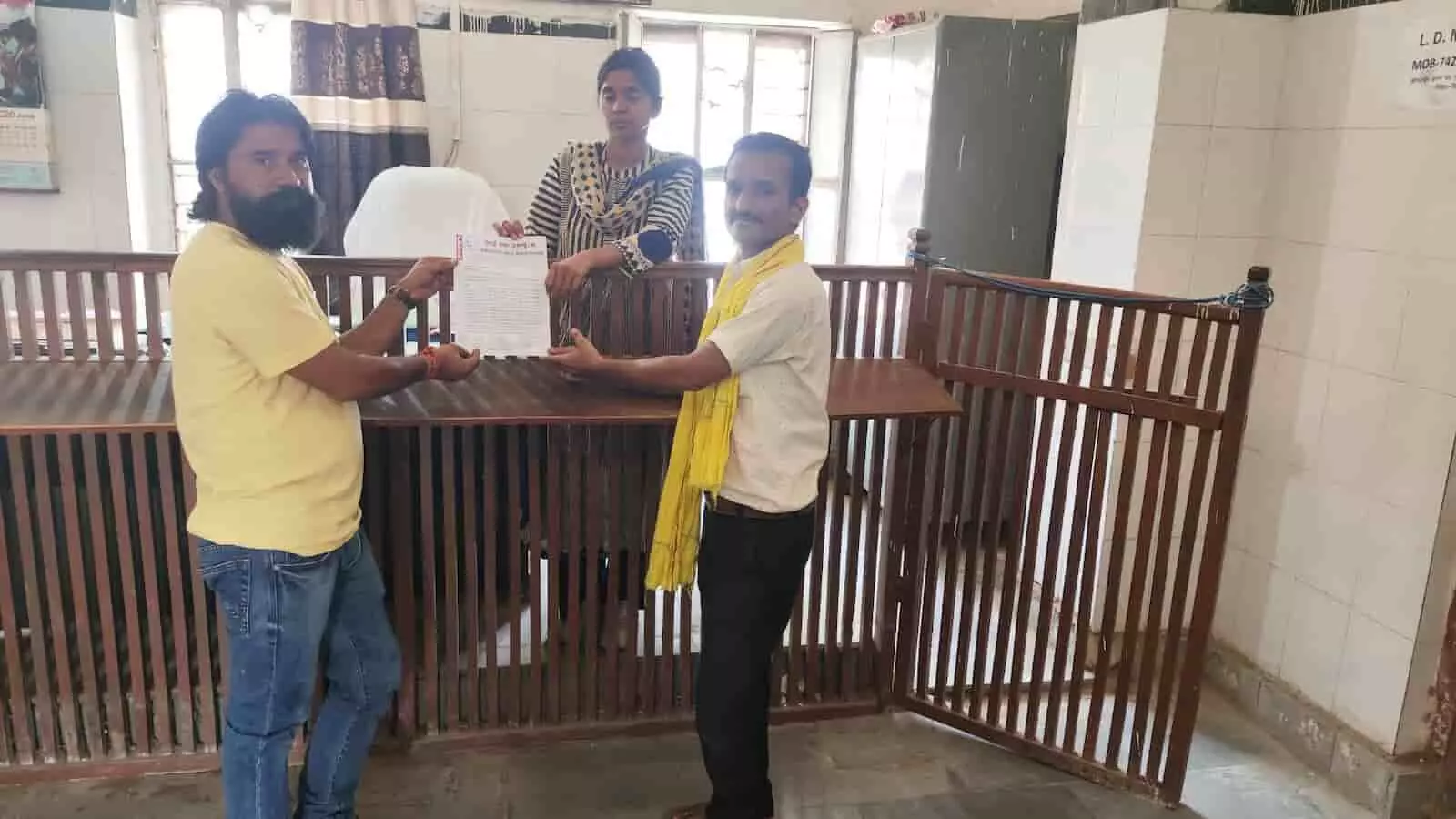 कार्यालय में एक महिला अधिकारी को लिखित ज्ञापन सौंपते हुए दो पुरुष प्रतिनिधि। कार्यालय में एक महिला अधिकारी को लिखित ज्ञापन सौंपते हुए दो पुरुष प्रतिनिधि।