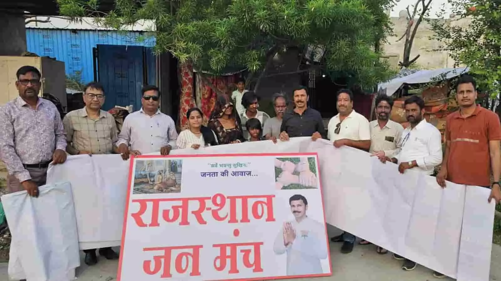 भीलवाड़ा में झुग्गी-झोपड़ियों के बाहर राजस्थान जन मंच का बैनर और तिरपाल पकड़े खड़े लोग। भीलवाड़ा में झुग्गी-झोपड़ियों के बाहर राजस्थान जन मंच का बैनर और तिरपाल पकड़े खड़े लोग।