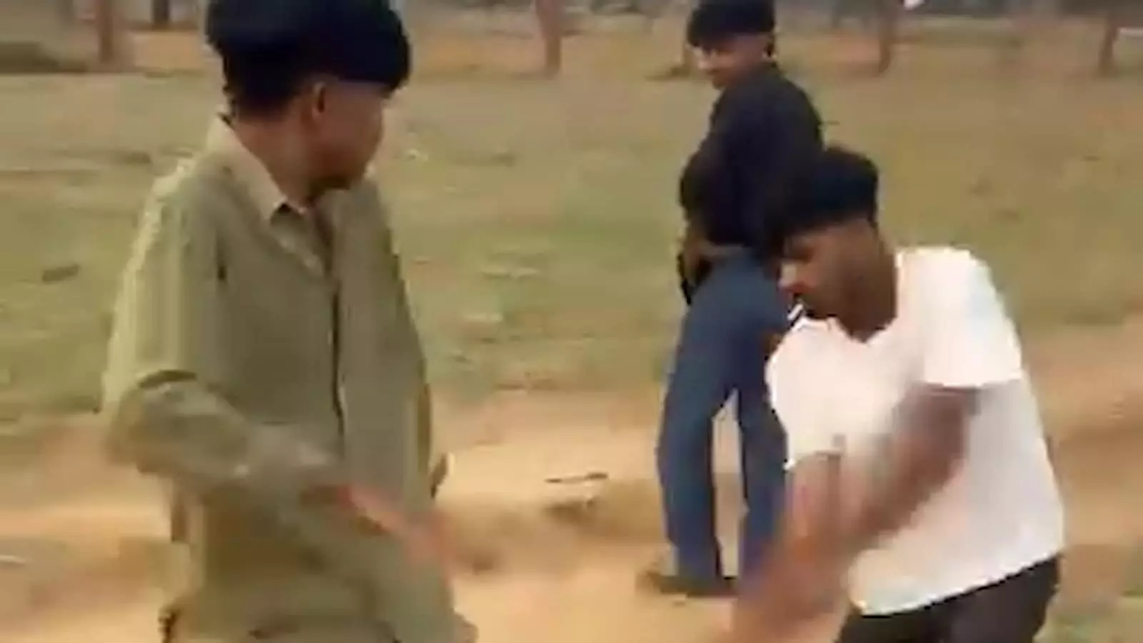 तस्वीर में मैदानी रास्ते पर तीन युवक खड़े और मारपीट की मुद्रा में दिखाई दे रहे हैं।
